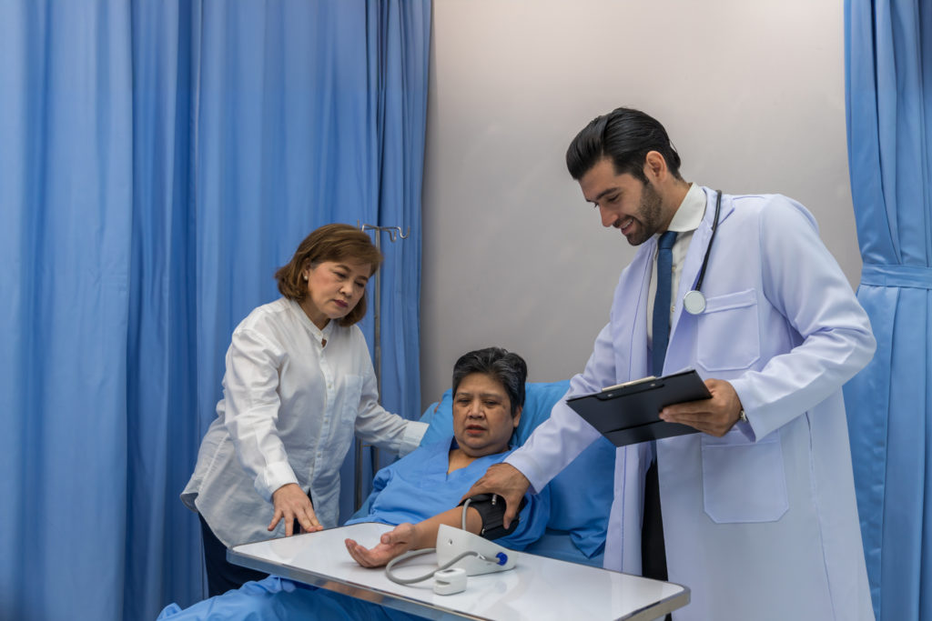 Médico visitando paciente na enfermaria. Homem hospitalizado deitado na cama enquanto o médico o examina.