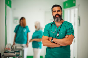 Retrato de um médico de braços cruzados no corredor do hospital.