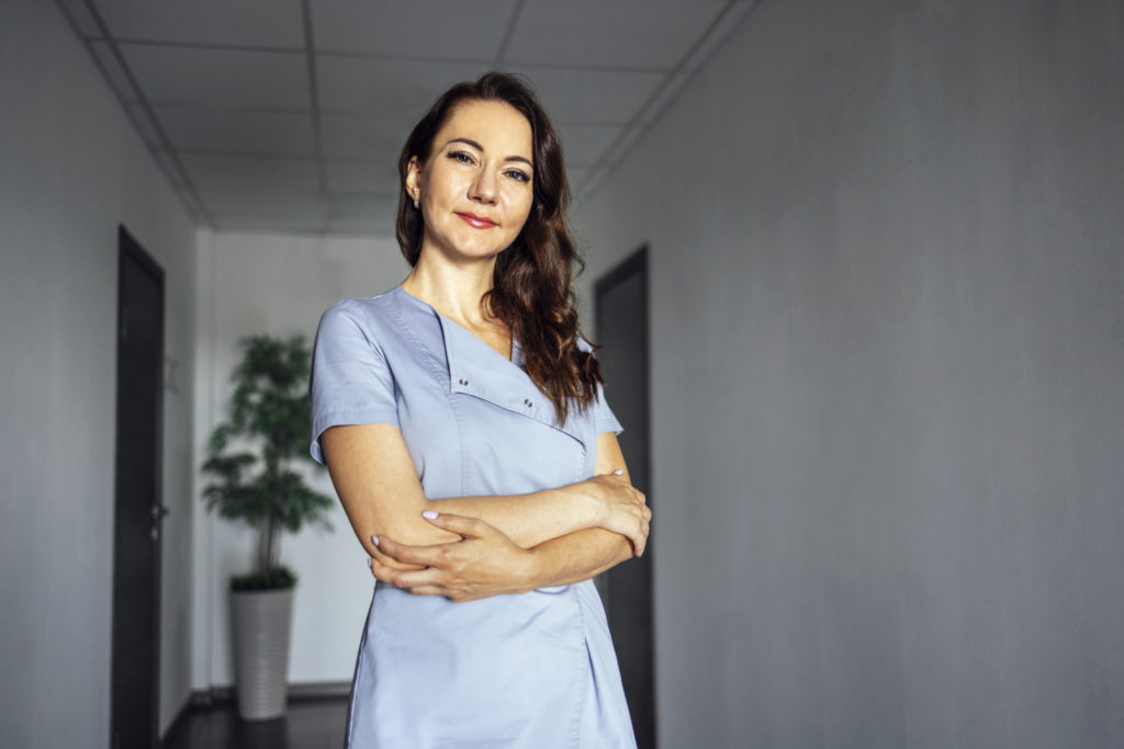 Médica sorridente, dentista, sobre fundo cinza claro