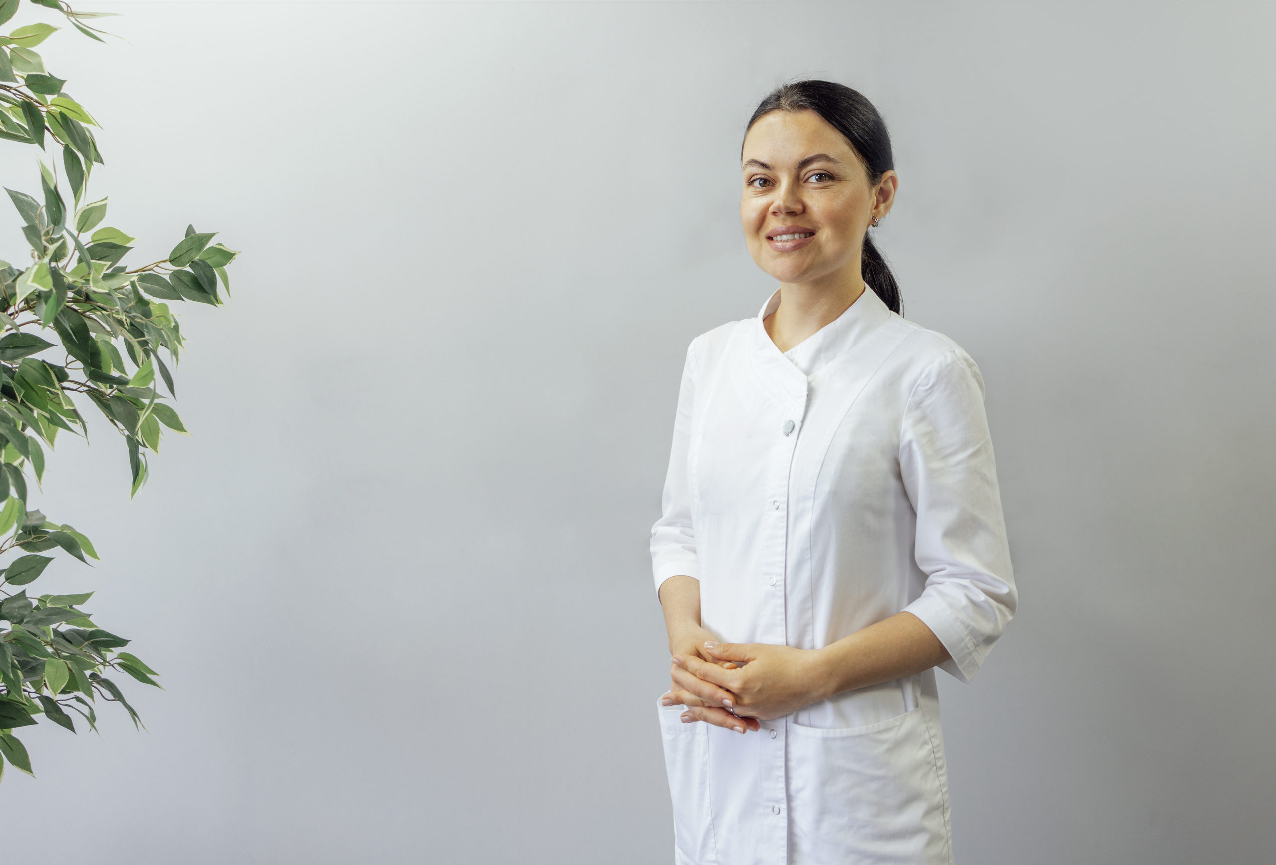 Médica sorridente, dentista, sobre fundo cinza claro