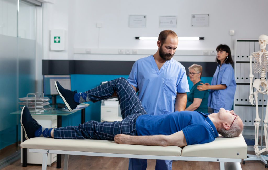 Homem com lesão muscular na perna recebendo massagem ortopédica