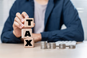 Imposto de ortografia de blocos de madeira com moedas e calculadora na mesa