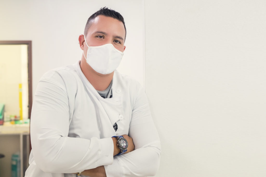 Foco superficial de um médico adulto usando uma máscara facial e um jaleco médico em um hospital