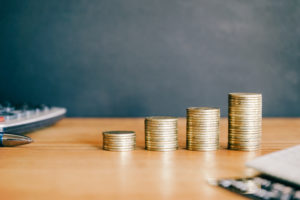 Pilha de moedas douradas sobre fundo preto com calculadora. Conceito financeiro e empresarial.