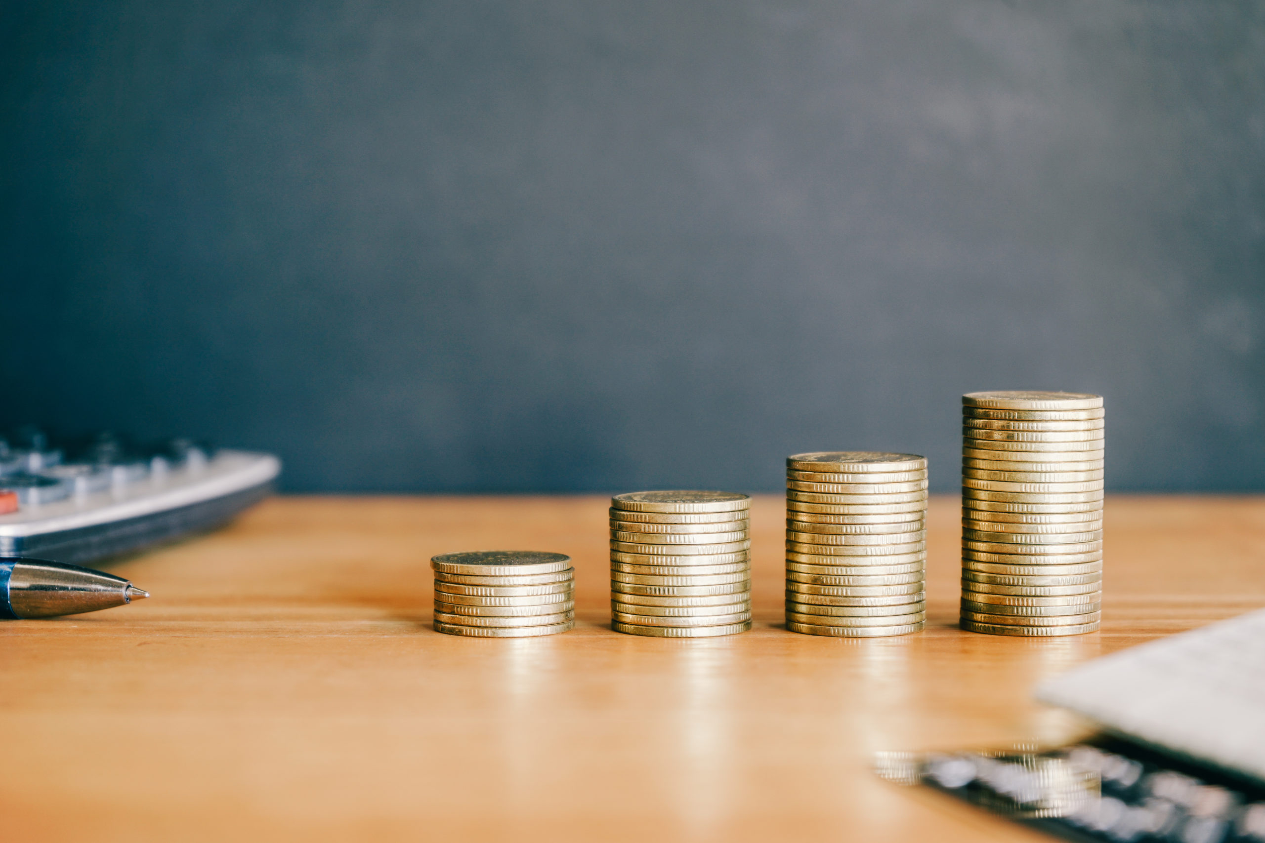 Pilha de moedas douradas sobre fundo preto com calculadora. Conceito financeiro e empresarial.