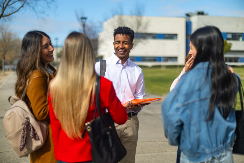 Professor universitário conversando e rindo com alunos no campus